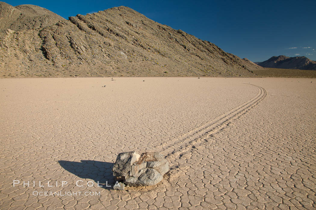 Sailing stone on the Death Valley Racetrack playa.  The sliding rocks, or sailing stones, move across the mud flats of the Racetrack Playa, leaving trails behind in the mud.  The explanation for their movement is not known with certainty, but many believe wind pushes the rocks over wet and perhaps icy mud in winter. Death Valley National Park, California, USA, natural history stock photograph, photo id 25331