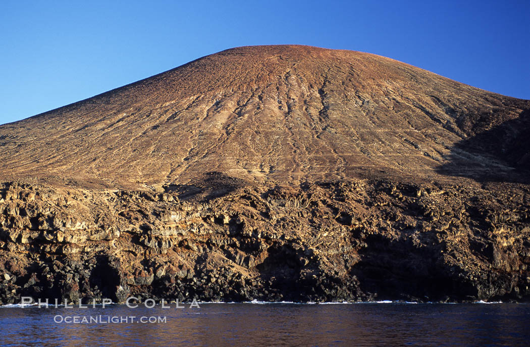 Red Cinder Cone and erodes sea cliffs overlook a fur seal colony and excellent dive site, west side of Guadalupe Island (Isla Guadalupe), Mexico.  Goat trails can be seen near the base of the cinder cone. Baja California, natural history stock photograph, photo id 09752