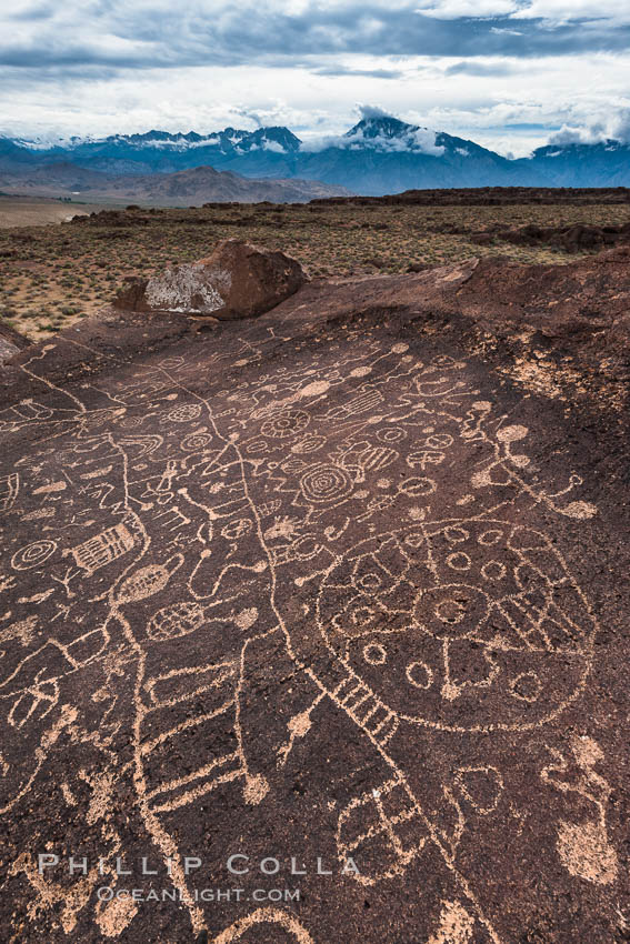 Sky Rock petroglyphs and storm clouds over the Eastern Sierran Nevada, near Bishop, California.  Hidden atop an enormous boulder in the Volcanic Tablelands lies Sky Rock, a set of petroglyphs that face the sky.  These superb examples of native American petroglyph artwork are thought to be Paiute in origin, but little is known about them. USA, natural history stock photograph, photo id 27001