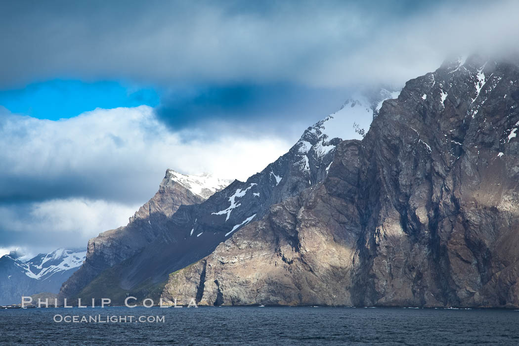 South Georgia Island coastline, showing the island's characteristic rugged topography.  56% of the island is covered by 161 glaciers, which have created numerous large bays and inlets that provide excellent habitat for marine animals and seabirds. Mountains meet the sea in steep-sided seacliffs covered with sparse vegetation.  The highest point on South Georgia Island is Mt. Paget at 2,915m., natural history stock photograph, photo id 24322