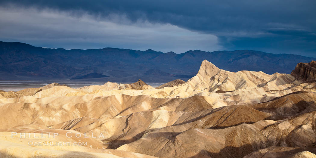 Sunrise at Zabriskie Point, Manly Beacon is lit by the morning sun while dark clouds lie on the horizon. Death Valley National Park, California, USA, natural history stock photograph, photo id 25257