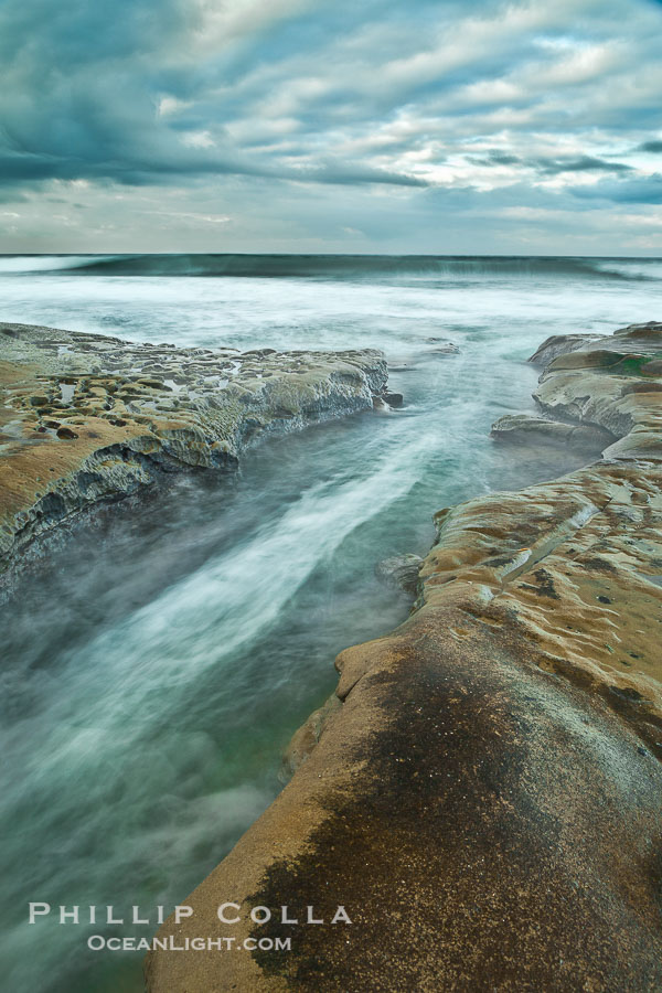 Waves wash over sandstone reef, clouds and sky., natural history stock photograph, photo id 26341