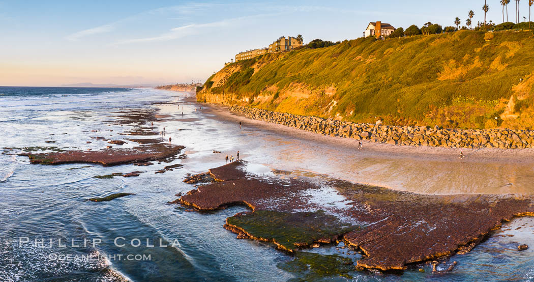 Swamis Beach Reefs Exposed by King Tides, people explore ocean reefs normally underwater but exposed on the extreme low tides known as King Tides. Aerial photo, Encinitas, California