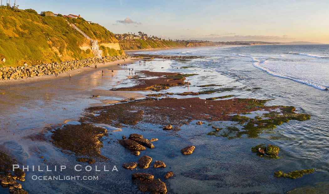 Swamis Beach Reefs Exposed by King Tides, people explore ocean reefs normally underwater but exposed on the extreme low tides known as King Tides. Aerial photo, Encinitas, California