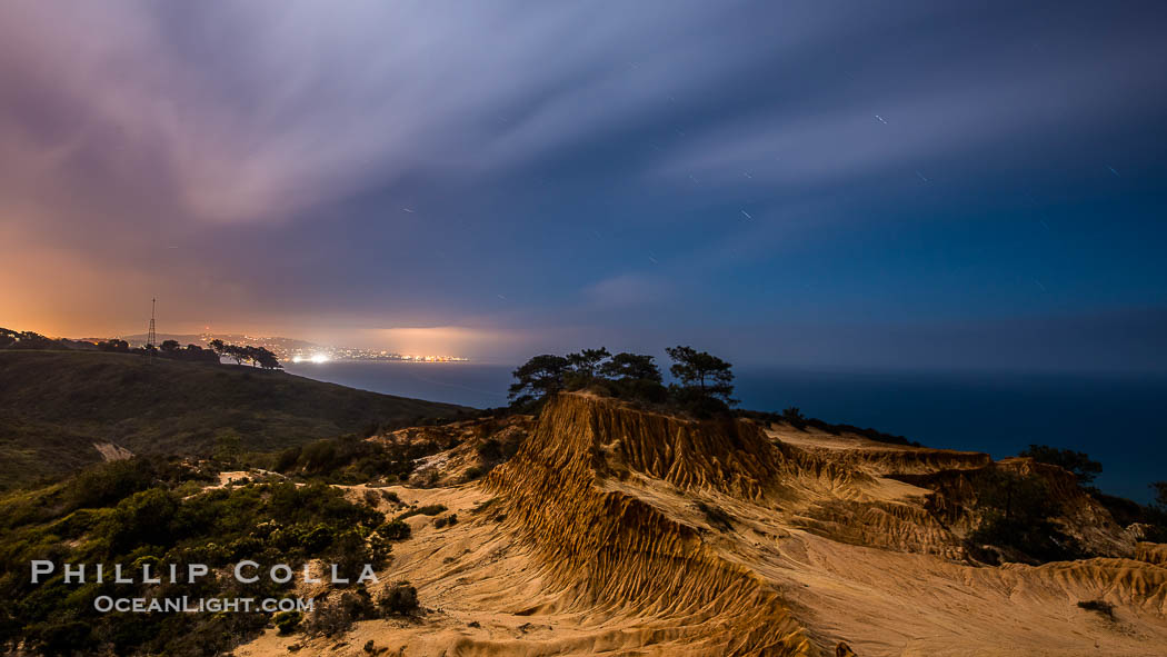 Torrey Pines State Reserve at Night, stars and clouds fill the night sky with the lights of La Jolla visible in the distance., natural history stock photograph, photo id 28406