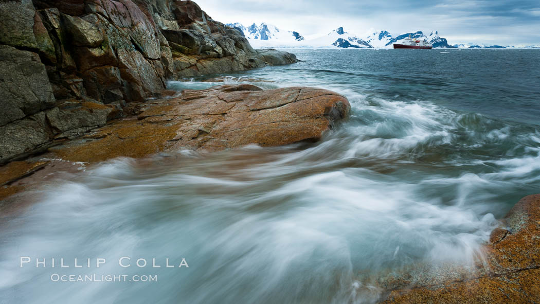 Waves rush in, sunset, Antarctica.  Ocean water rushes ashore over the rocky edge of Peterman Island, Antarctica. Antarctic Peninsula, natural history stock photograph, photo id 25620