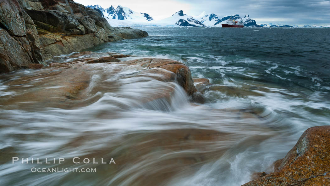 Waves rush in, sunset, Antarctica.  Ocean water rushes ashore over the rocky edge of Peterman Island, Antarctica. Antarctic Peninsula, natural history stock photograph, photo id 25636