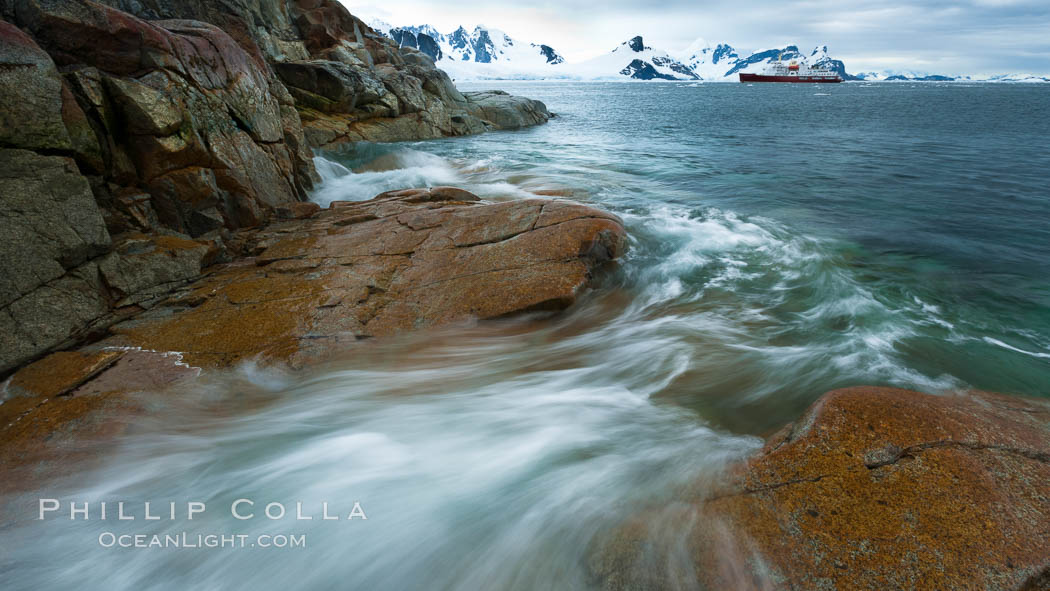 Waves rush in, sunset, Antarctica.  Ocean water rushes ashore over the rocky edge of Peterman Island, Antarctica. Antarctic Peninsula, natural history stock photograph, photo id 25637