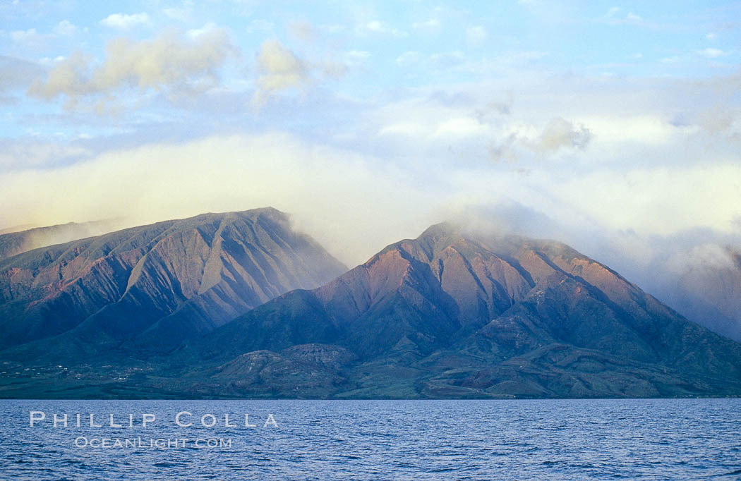 West Maui mountains rise above the coast of Maui, with clouds flanking the ancient eroded remnants of a volcano. Hawaii, USA, natural history stock photograph, photo id 05860