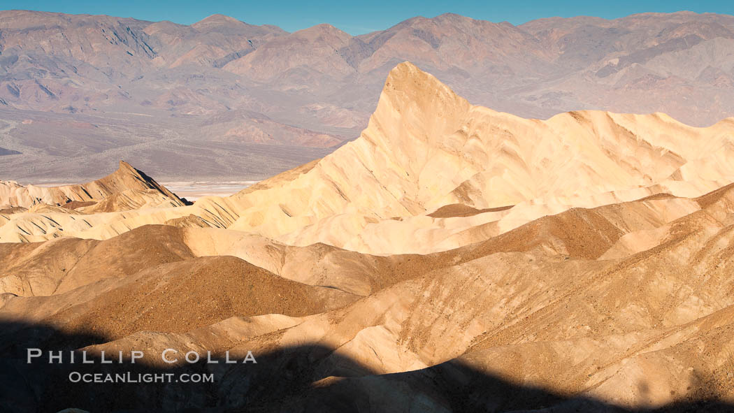 Zabriskie Point, sunrise.  Manly Beacon rises in the center of an eroded, curiously banded area of sedimentary rock, with the Panamint Mountains visible in the distance. Death Valley National Park, California, USA, natural history stock photograph, photo id 15575