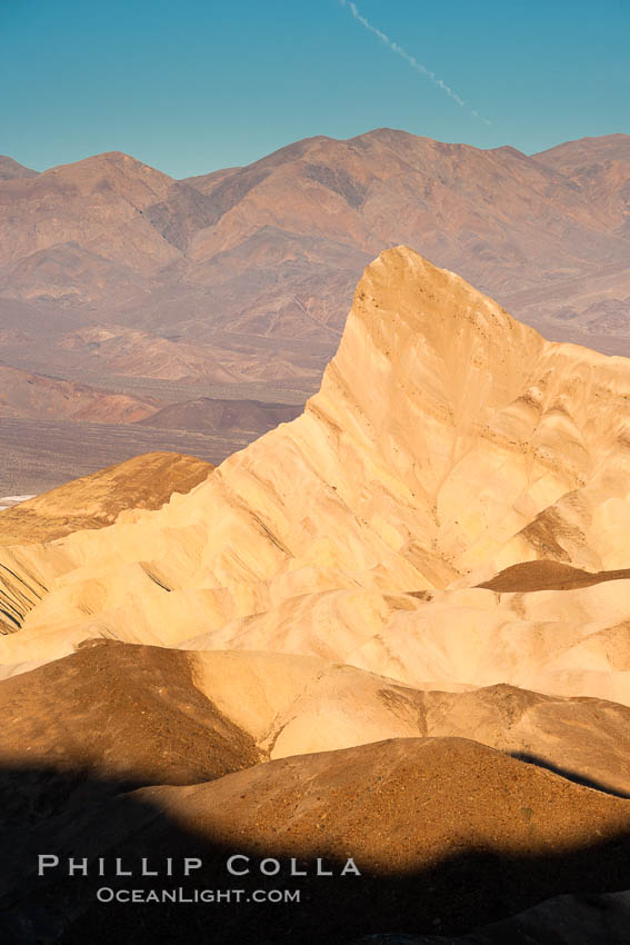 Zabriskie Point, sunrise.  Manly Beacon rises in the center of an eroded, curiously banded area of sedimentary rock, with the Panamint Mountains visible in the distance. Death Valley National Park, California, USA, natural history stock photograph, photo id 15586