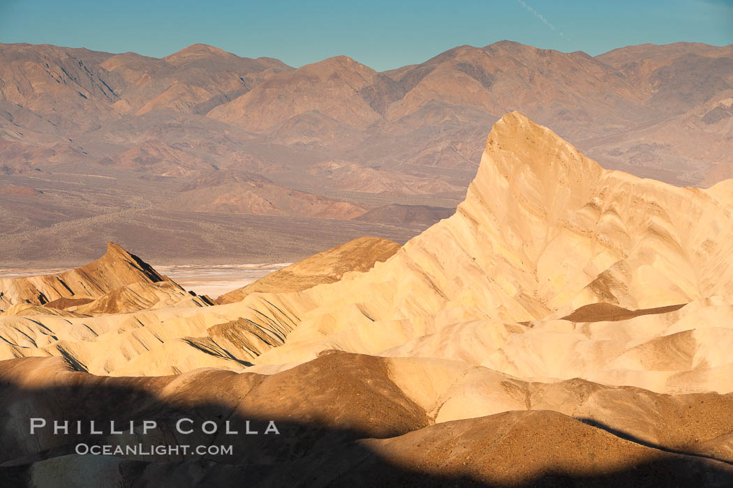 Zabriskie Point, sunrise.  Manly Beacon rises in the center of an eroded, curiously banded area of sedimentary rock, with the Panamint Mountains visible in the distance. Death Valley National Park, California, USA, natural history stock photograph, photo id 15602