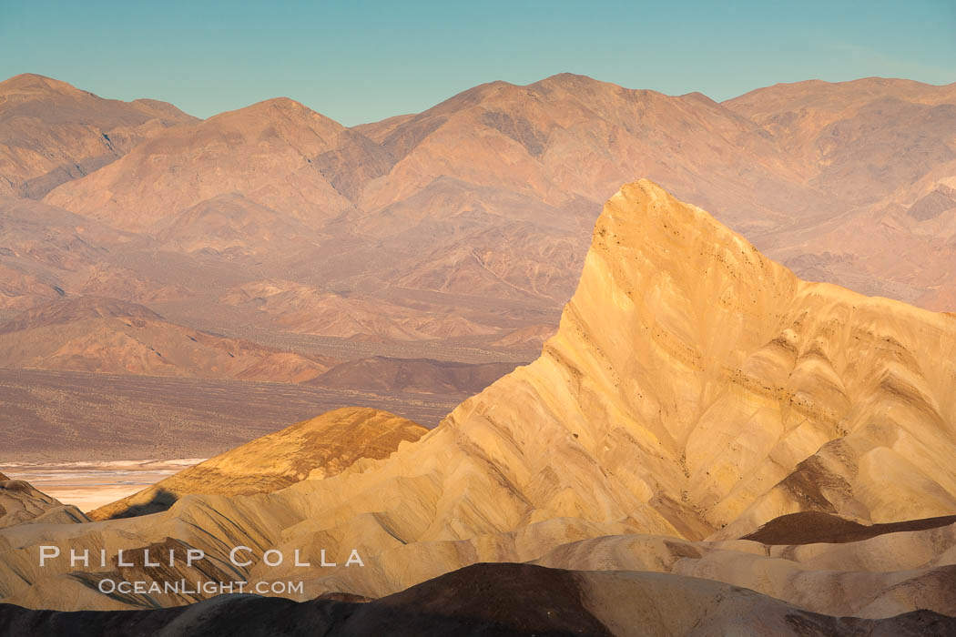 Zabriskie Point, sunrise.  Manly Beacon rises in the center of an eroded, curiously banded area of sedimentary rock, with the Panamint Mountains visible in the distance. Death Valley National Park, California, USA, natural history stock photograph, photo id 15618